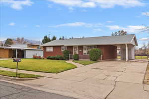 Ranch-style house with concrete driveway, an attached carport, roof with shingles, and brick siding