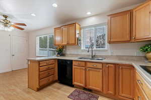 Kitchen with a peninsula, light countertops, black dishwasher, brown cabinetry, and healthy amount of natural light