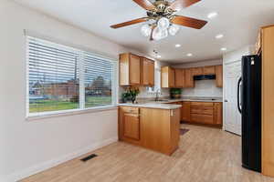 Kitchen with light countertops, black appliances, a peninsula, recessed lighting, and brown cabinets