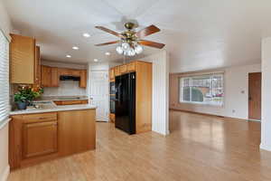 Kitchen with recessed lighting, black appliances, open floor plan, ceiling fan, and light wood-style flooring