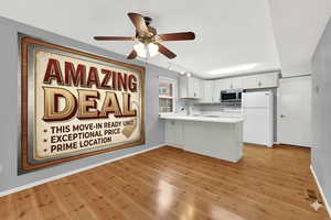 Kitchen featuring white appliances, light countertops, a ceiling fan, rail lighting, and a peninsula