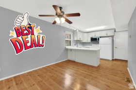 Kitchen with freestanding refrigerator, a peninsula, light countertops, white cabinetry, and ceiling fan