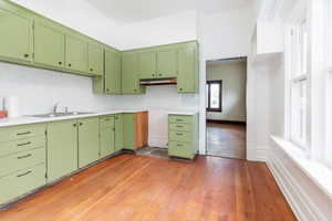Kitchen featuring green cabinetry, dark wood-style floors, and light countertops