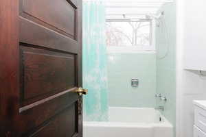Bathroom with shower / bath combination with curtain and vanity