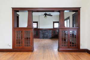 Unfurnished dining area with light wood-style flooring, a ceiling fan, a fireplace, and plenty of natural light