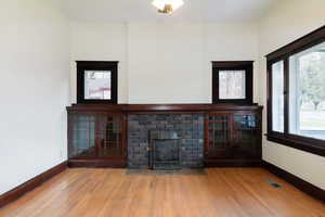 Unfurnished living room featuring wood finished floors, healthy amount of natural light, and a fireplace