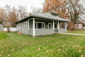 Bungalow with a front yard, a porch, a chimney, and roof with shingles