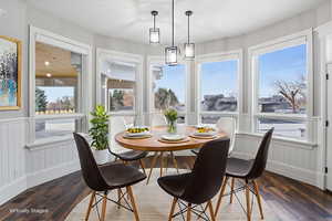 Dining space with wood finished floors, healthy amount of natural light, and wainscoting