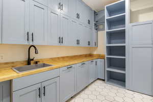 Kitchen with butcher block counters and gray cabinetry