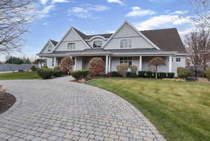 Shingle-style home with a standing seam roof, a porch, a metal roof, and decorative driveway