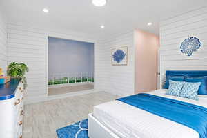 Bedroom with wood walls, light wood-style flooring, and recessed lighting