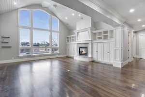 Unfurnished living room featuring a glass covered fireplace, dark wood finished floors, high vaulted ceiling, and recessed lighting