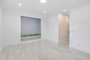 Spare room featuring wooden walls, light wood finished floors, and recessed lighting