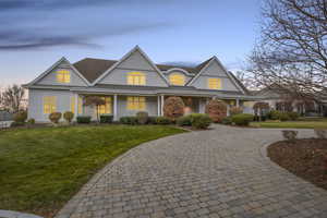 Shingle-style home featuring a lawn, curved driveway, and a porch