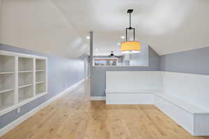 Unfurnished dining area featuring lofted ceiling, built in features, light wood finished floors, recessed lighting, and a ceiling fan