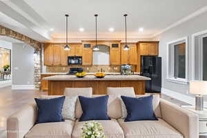 Kitchen with open floor plan, a center island, black appliances, tasteful backsplash, and light stone counters