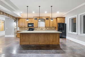 Kitchen with brown cabinets, black appliances, tasteful backsplash, light stone counters, and a center island