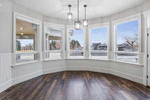 Unfurnished dining area with dark wood-style flooring
