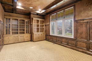 Spare room featuring coffered ceiling, beam ceiling, ornamental molding, and carpet