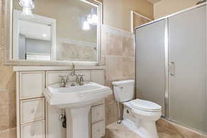 Bathroom with a stall shower, tile walls, and light tile patterned floors