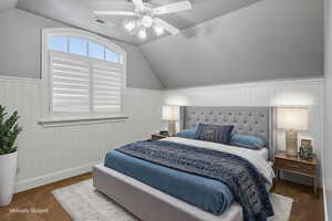 Bedroom featuring vaulted ceiling, ceiling fan, and a wainscoted wall