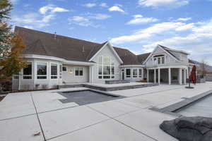 Rear view of property featuring a patio area, a swimming pool, and roof with shingles