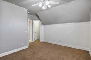 Additional living space with lofted ceiling, carpet, and ceiling fan