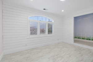 Spare room with wooden walls, wood finished floors, and recessed lighting