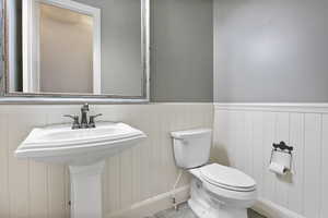 Half bath featuring toilet and wainscoting