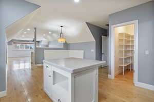 Kitchen with white cabinets, light wood finished floors, pendant lighting, recessed lighting, and lofted ceiling