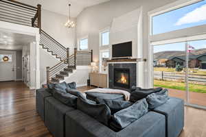 Living room with high vaulted ceiling, wood finished floors, a premium fireplace, plenty of natural light, and stairs