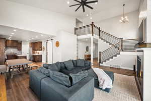 Living room with a barn door, a lit fireplace, light wood-style floors, high vaulted ceiling, and recessed lighting