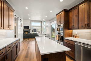 Kitchen with backsplash, appliances with stainless steel finishes, a barn door, a kitchen island, and recessed lighting