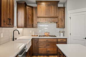 Kitchen featuring light stone countertops, tasteful backsplash, brown cabinets, light wood-type flooring, and stainless steel appliances