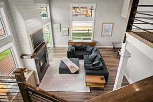 Living area featuring wood finished floors, a glass covered fireplace, and a high ceiling
