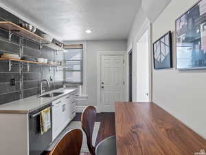 Kitchen featuring open shelves, white cabinetry, stainless steel dishwasher, a textured ceiling, and dark wood-style floors