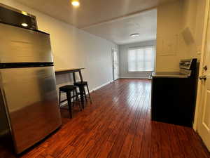 Kitchen with freestanding refrigerator, black electric range, dark wood-type flooring, electric panel, and light countertops