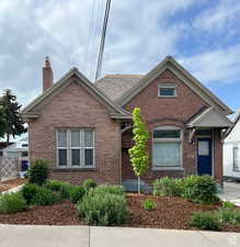 View of front of house featuring brick siding and a chimney