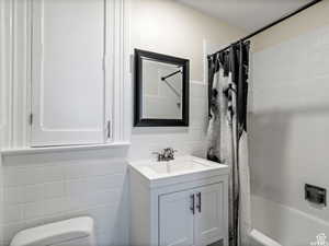 Full bath featuring tile walls, shower / tub combo with curtain, and vanity