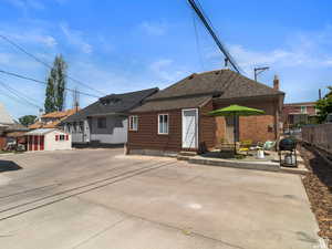 Back of property with a patio, roof with shingles, a chimney, a shed, and brick siding