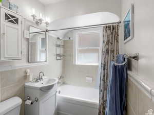 Full bath featuring tile walls, shower / tub combo with curtain, and vanity