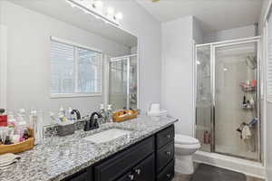 Full bath featuring vanity, a stall shower, plenty of natural light, a textured ceiling, and dark wood finished floors