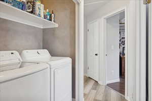 Laundry room with washing machine and clothes dryer and light wood-style floors