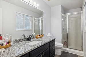 Full bath featuring vanity, a shower stall, and a textured ceiling