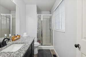 Full bathroom featuring vanity, a shower stall, a textured ceiling, and dark wood-style floors