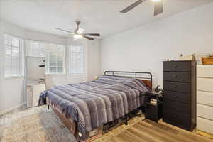 Bedroom featuring light wood finished floors, a textured ceiling, and ceiling fan