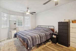 Bedroom featuring light wood-type flooring, ceiling fan, and a textured ceiling