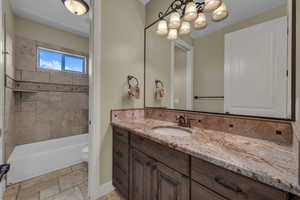 Full bath with vanity, stone tile floors,  shower combination, and a chandelier