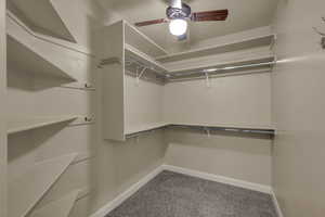 Walk in closet with light colored carpet and ceiling fan