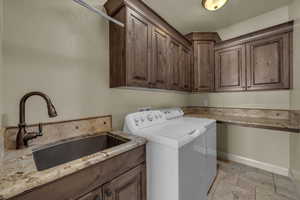 Washroom with stone tile flooring, washing machine and clothes dryer, and cabinet space